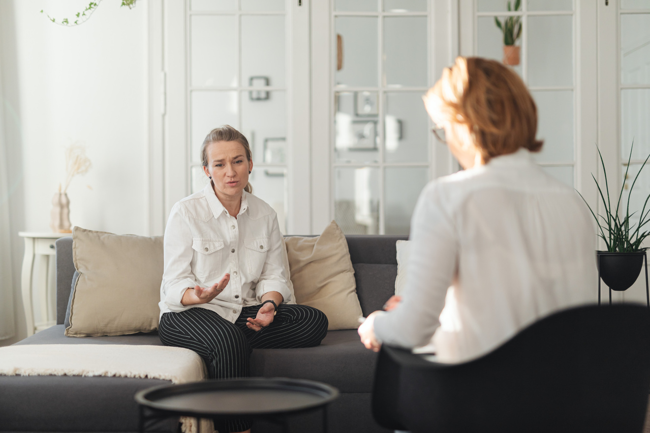 Woman in White Long Sleeves Sitting on Gray Sofa